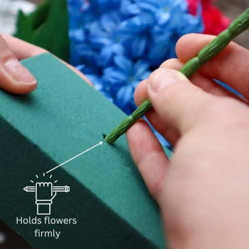 A person's hands inserting a green flower stem into a block of green floral foam, with the text "Holds flowers firmly" pointing to the foam.