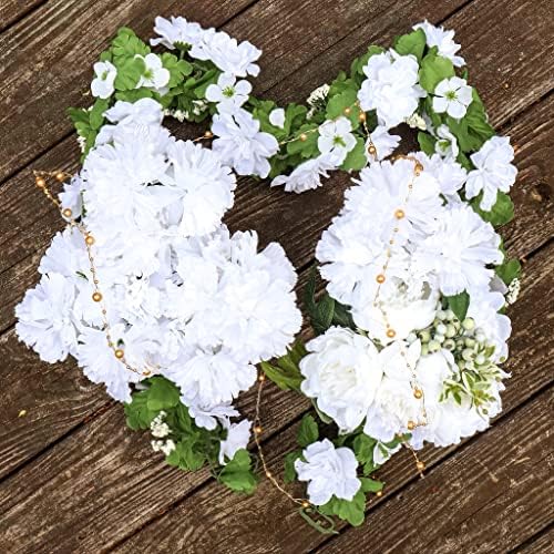 Two white floral arrangements with green accents, likely artificial, arranged on a rustic wooden surface.