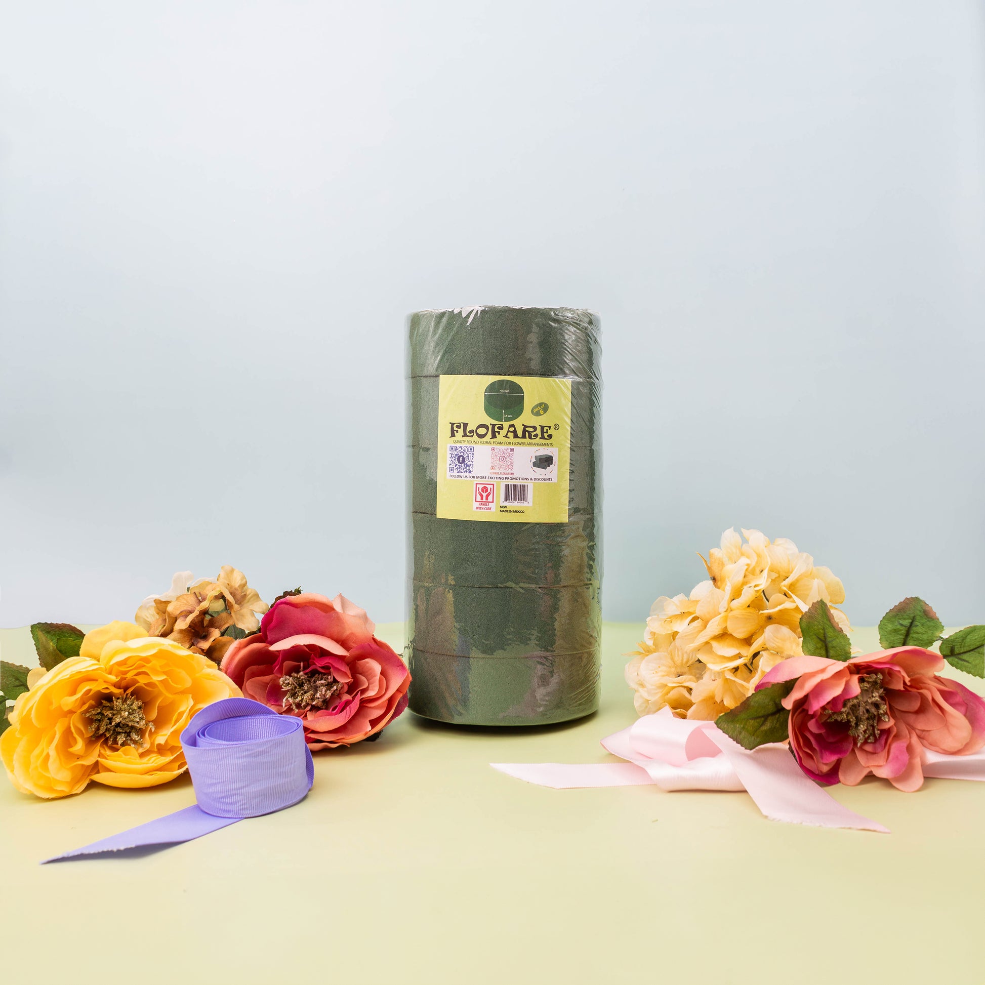 Flofare floral tape roll and assorted artificial flowers and ribbons on a light green surface.
